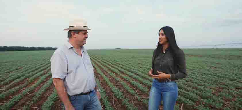 O produtor rural Paulo Assunção e a engenheira-agrônoma Flávia Cunha conversando diante de uma lavoura de soja
